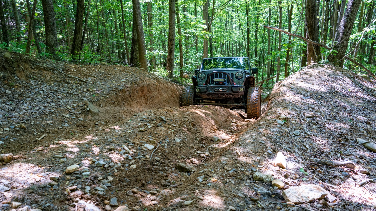 Przednie koła SUVa 4x4 wbijają się w luźne błoto na stromym podjeździe